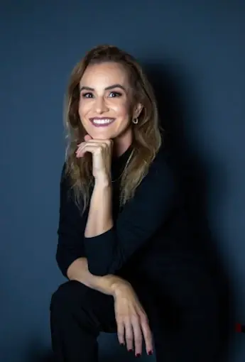 Paula Razuk em retrato profissional com fundo azul.